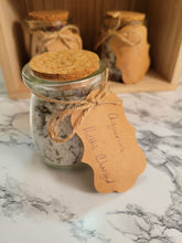 Load image into Gallery viewer, Close up of a jar of Aquarius-inspired, reiki-charged bath salts in 4 oz glass jar with cork and paper tag.
