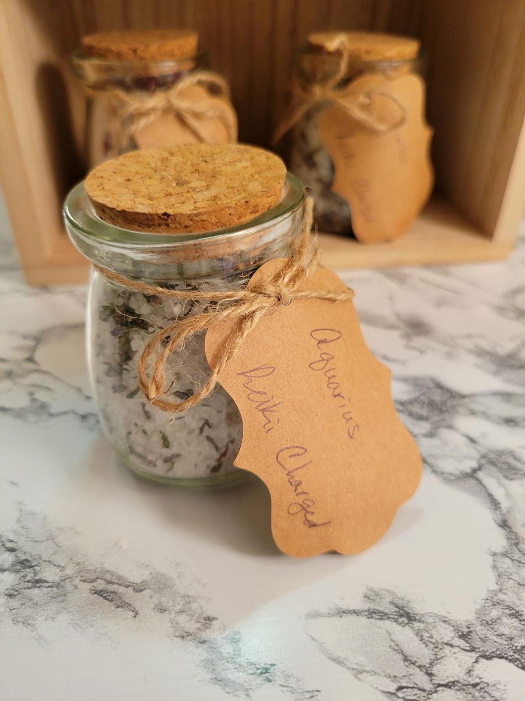 Close up of a jar of Aquarius-inspired, reiki-charged bath salts in 4 oz glass jar with cork and paper tag.