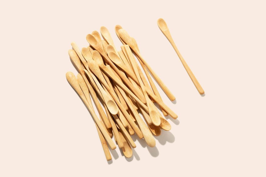 Photo of a pile of long handled bamboo spoons intended for coffee and/or tea